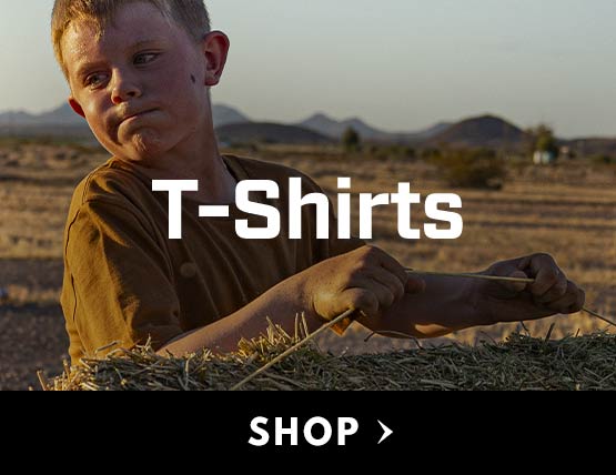 A young boy in a Carhartt t-shirt holding a bale of hay