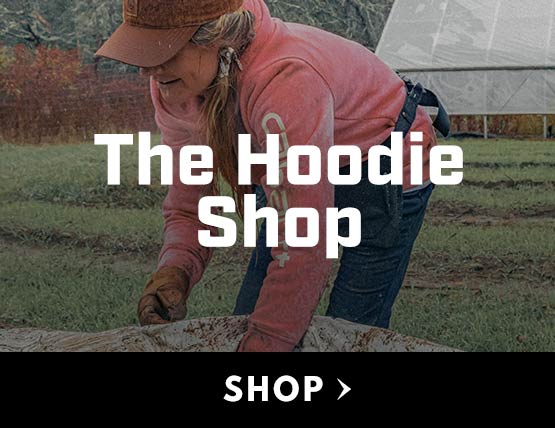 A woman working outdoors in a pink Carhartt hoodie sweatshirt. 