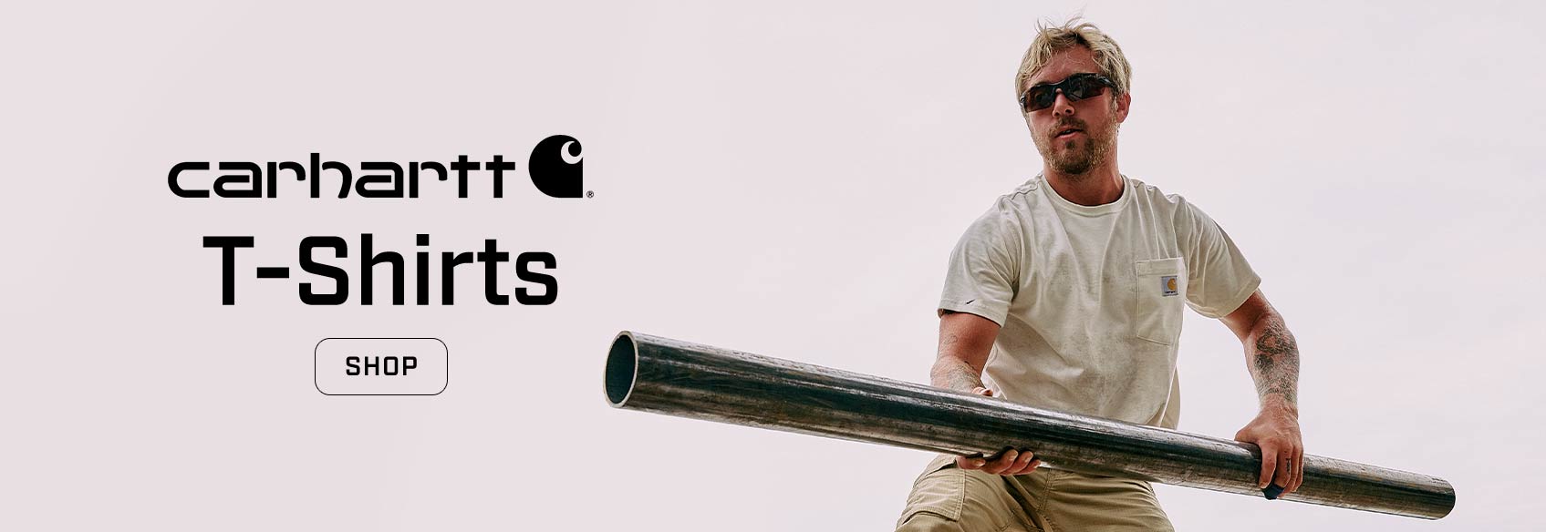 A man holding a large pipe wearing a white Carhartt t-shirt.