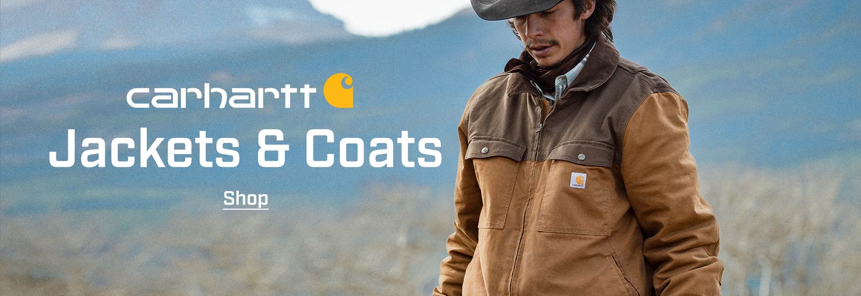 A man wearing a Carhartt jacket in a field. 