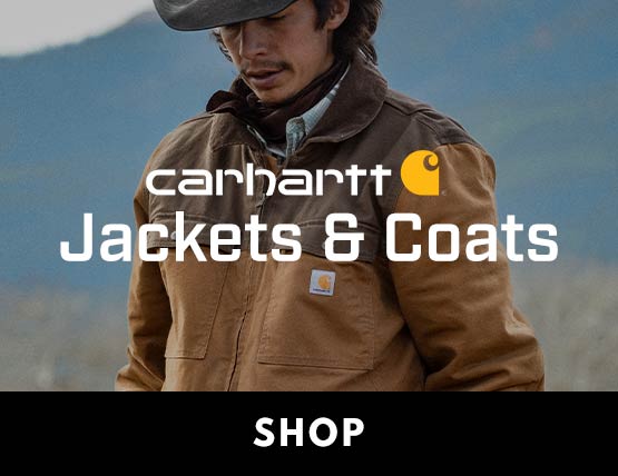 A man wearing a Carhartt jacket in a field. 