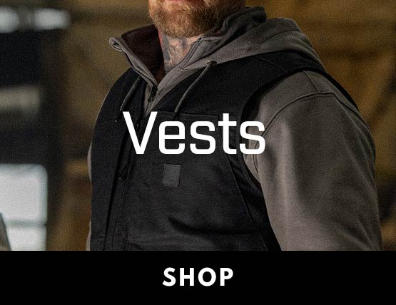 a man wearing a carhartt vest in a barn