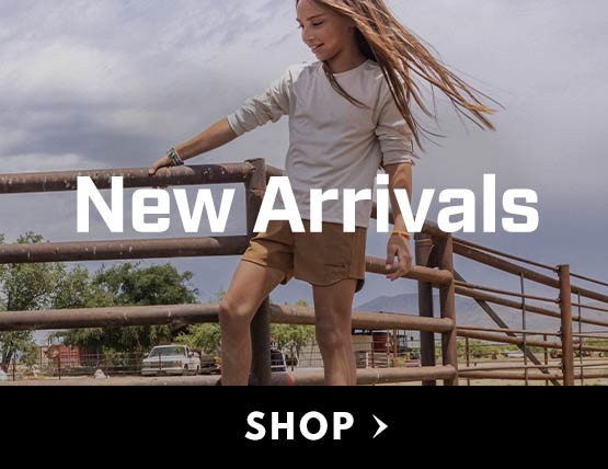 A young girl wearing shorts and a Carhartt t-shirt walking along a fence