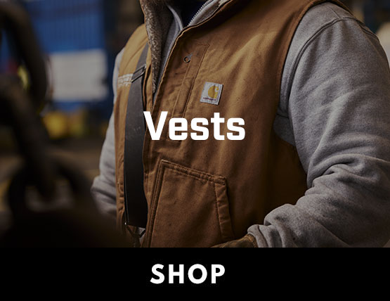 A man wearing a duck brown Carhartt vest with a gray sweatshirt underneath