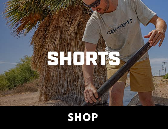 A man working in the sun wearing Carhartt shorts and holding a shovel
