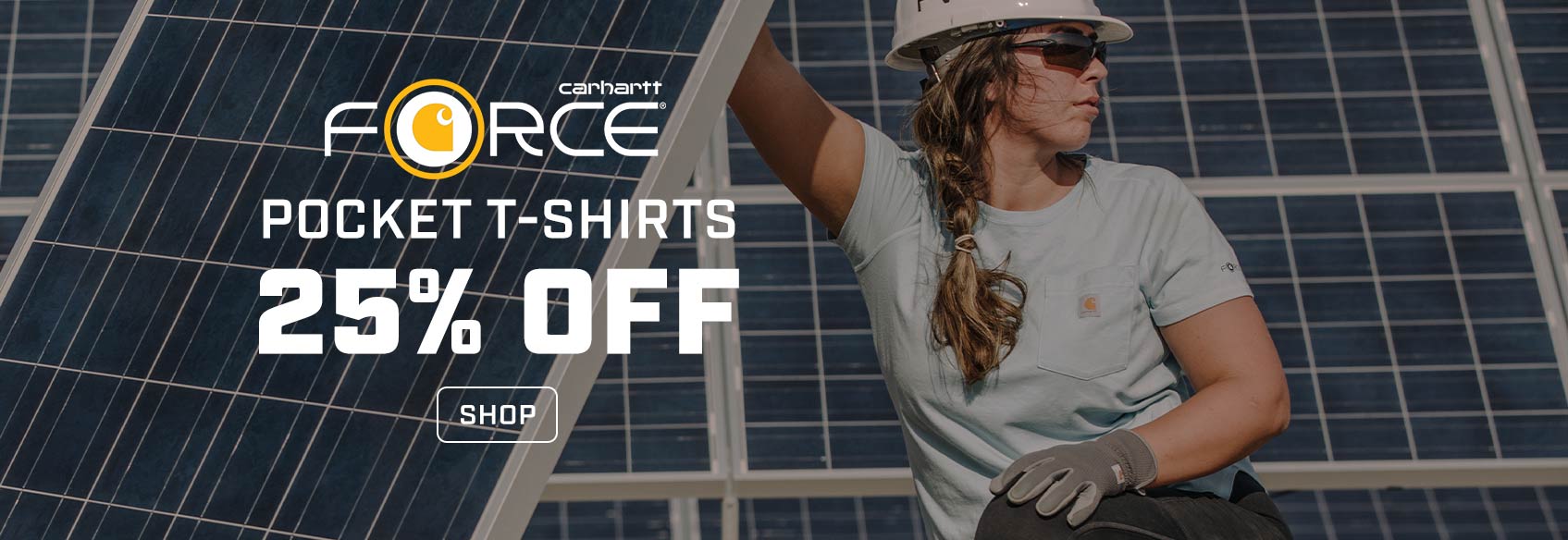 A woman working outside in a solar panel field weiring a hard hat and Carhartt t-shirt