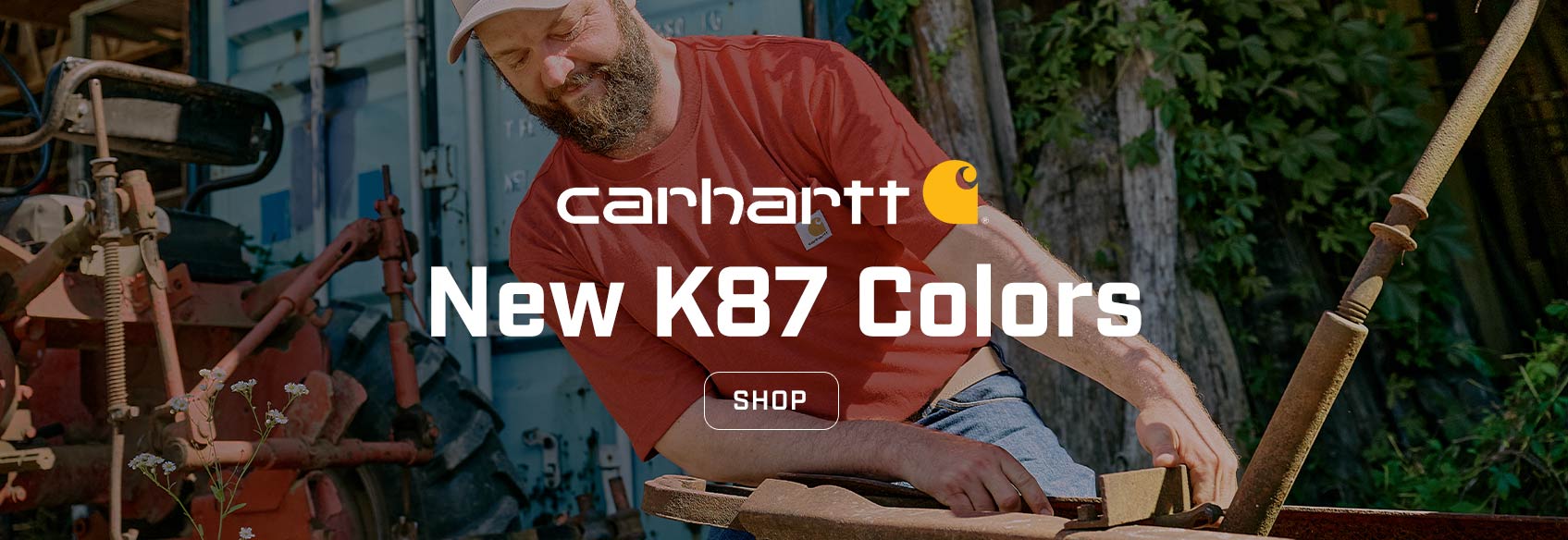 A man working outside in the sun wearing a red Carhartt K87 pocket t-shirt.