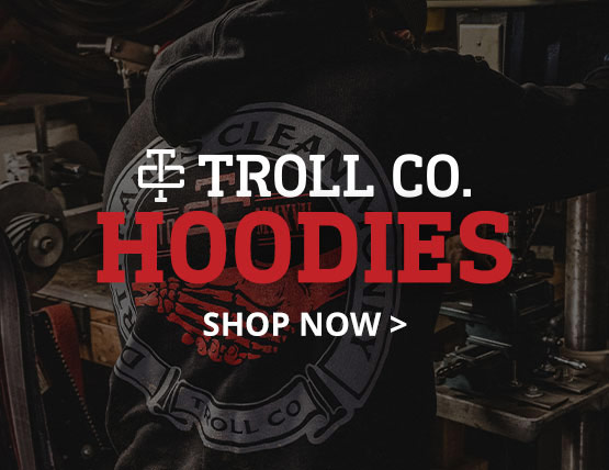 A man in a shop wearing a Troll Co. hoodie