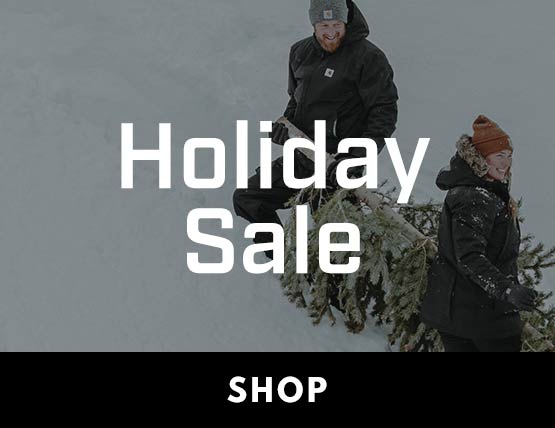 Holiday Sale A couple carrying a pine tree through the snow.