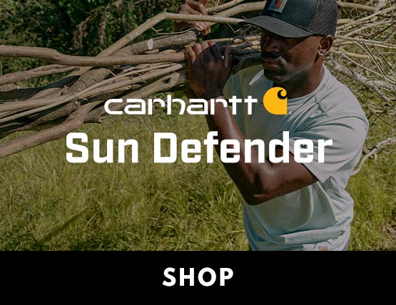A man carrying sticks outside wearing a Carhartt shirt and hat.