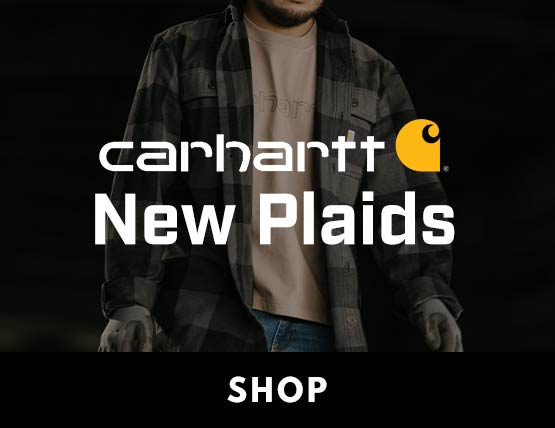 A man wearing a button up plaid Carhartt shirt in a dimly lit room