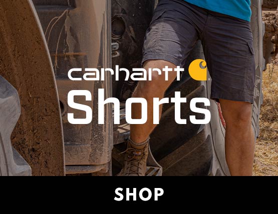 A man stepping out of a tractor wearing Carhartt shorts. 