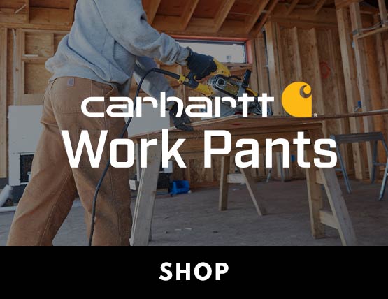 A carpenter sawing a board wearing Carhartt work pants